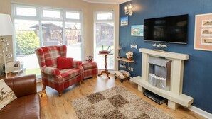 A living room with a fireplace, a television, and a plaid sofa. - 6 Badgers Retreat (Richmond)