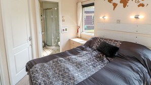 A bedroom with a bed, a window, a shower, and a world map on the wall. - 6 Badgers Retreat (Richmond)
