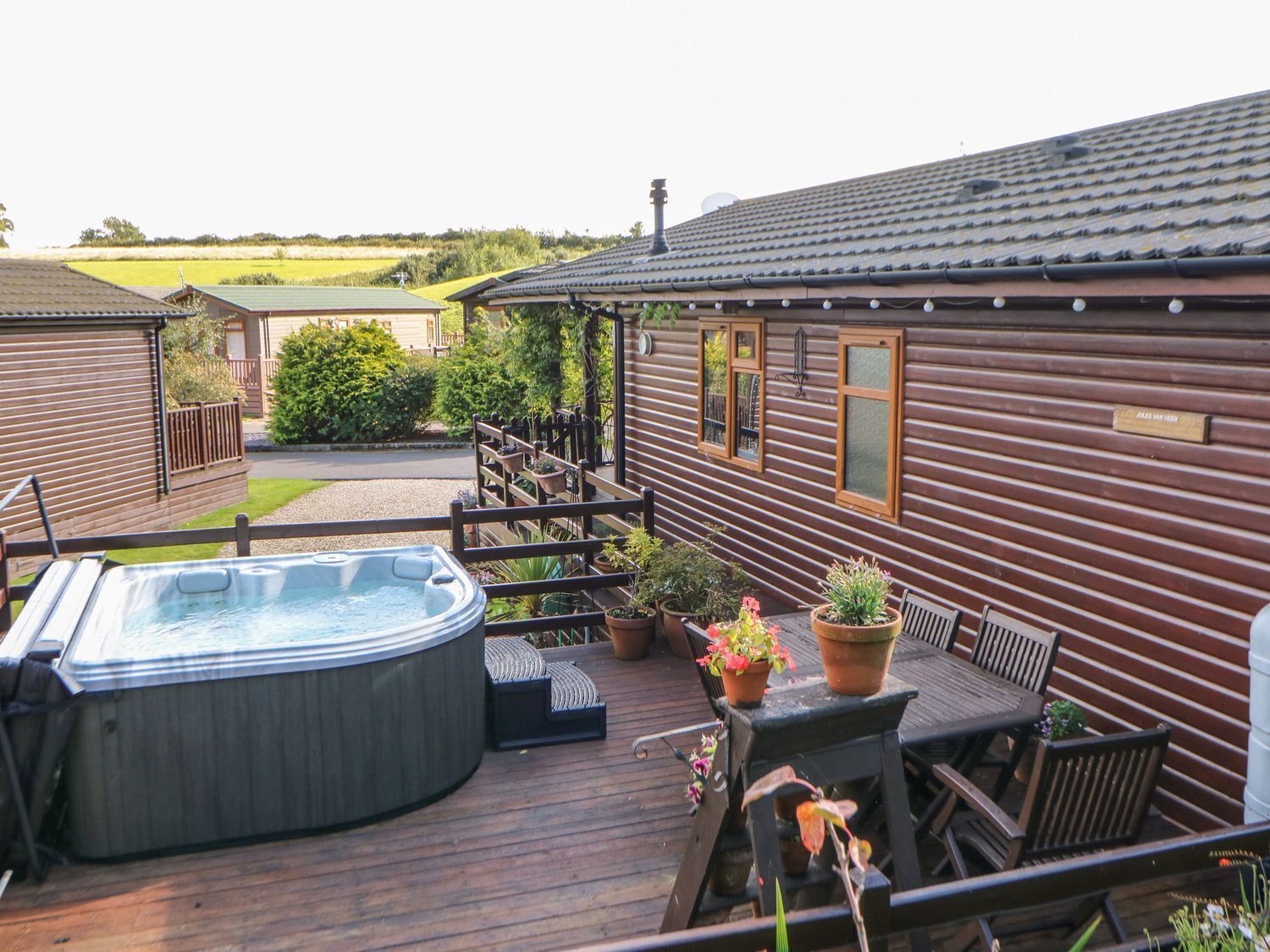 A wooden cabin with a hot tub, outdoor seating, and potted plants.