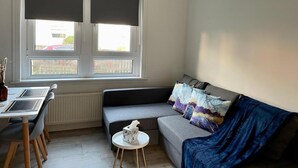 Un espacio habitable compacto con un sofá, una peque ña mesa redonda y un comedor con sillas.