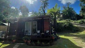 Una casa moderna con un porche cubierto, rodeada de exuberante follaje y palmeras.