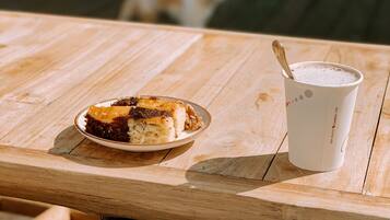 A wooden table with a plate of food and a cup of coffee.