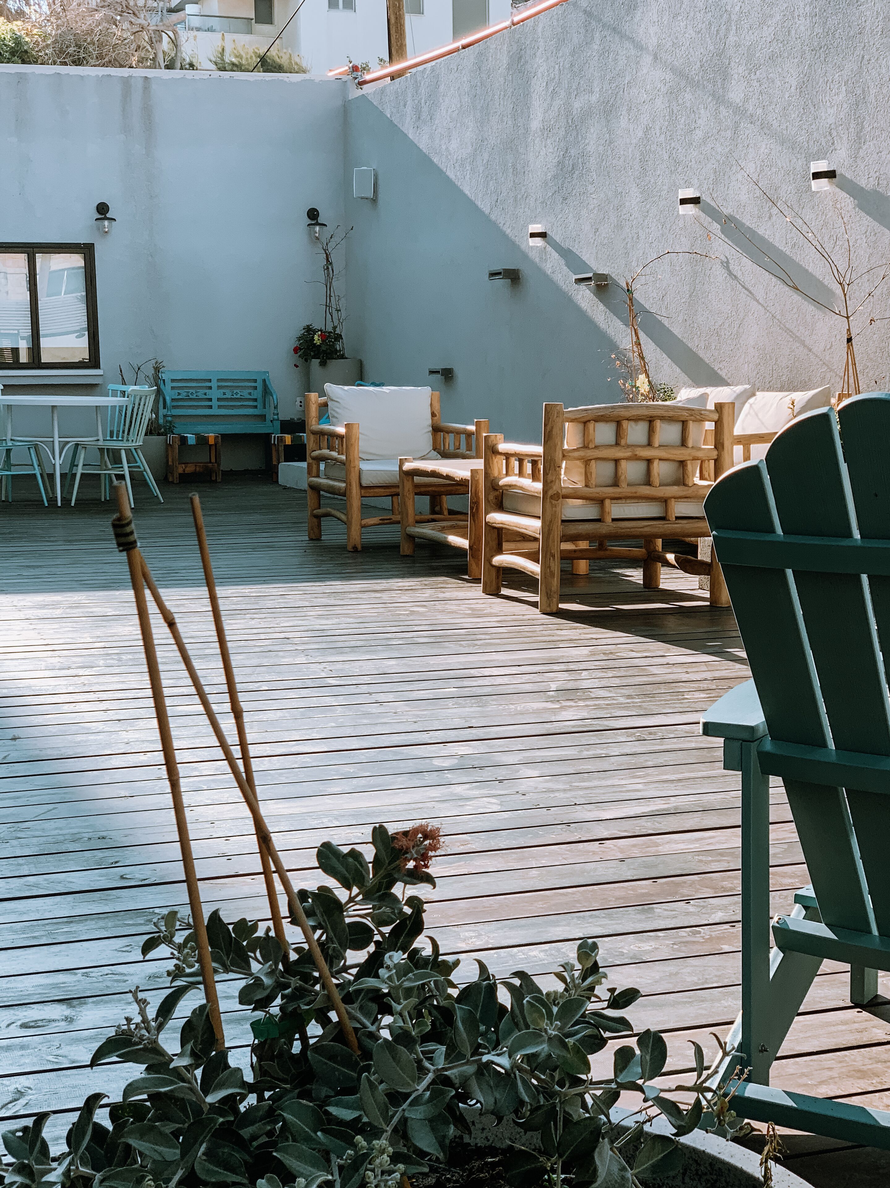 Eine Holzterrasse mit Gartenmöbeln, darunter Stühle und ein Tisch.