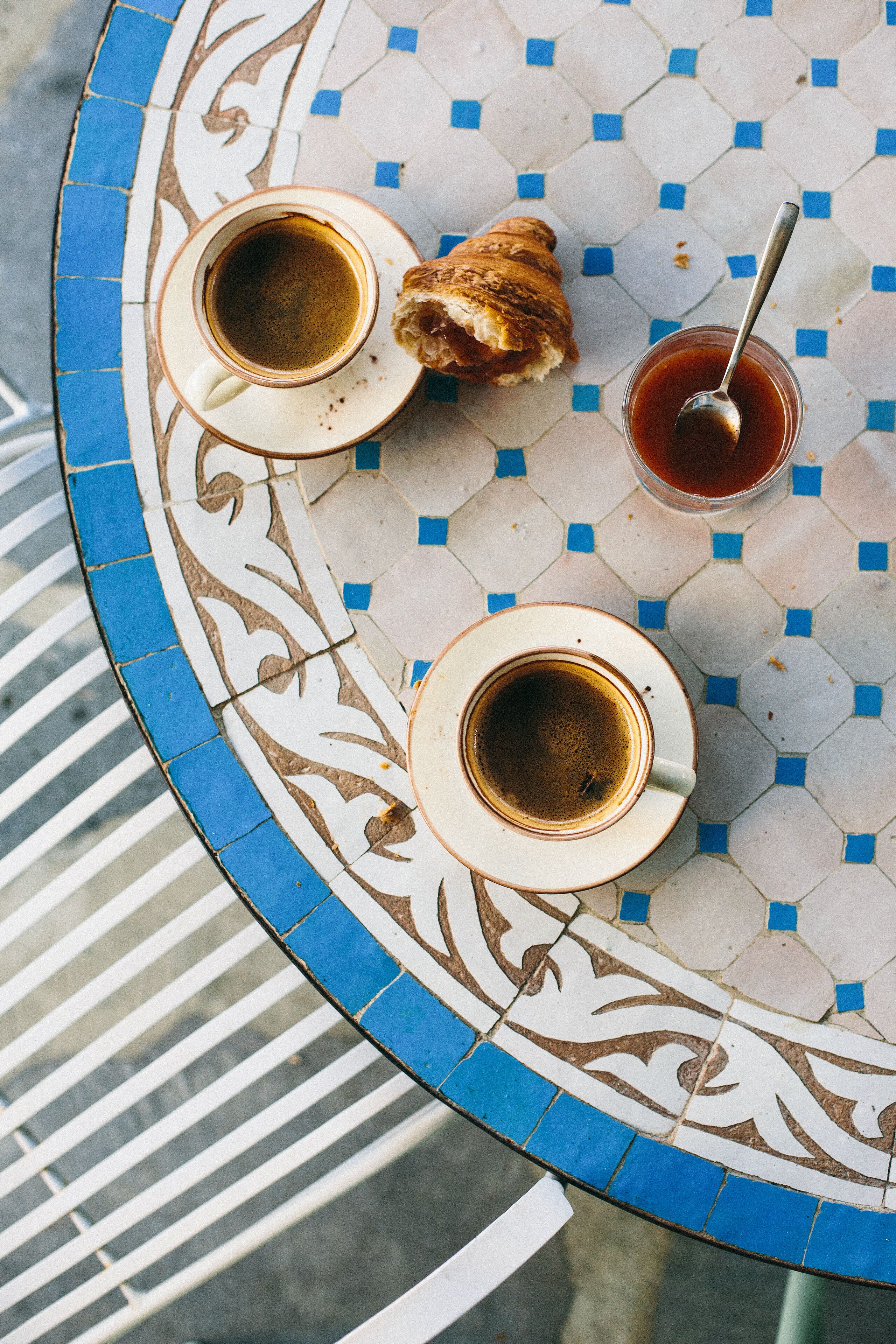 Una mesa con dos tazas de café, un pastel y una taza de té.