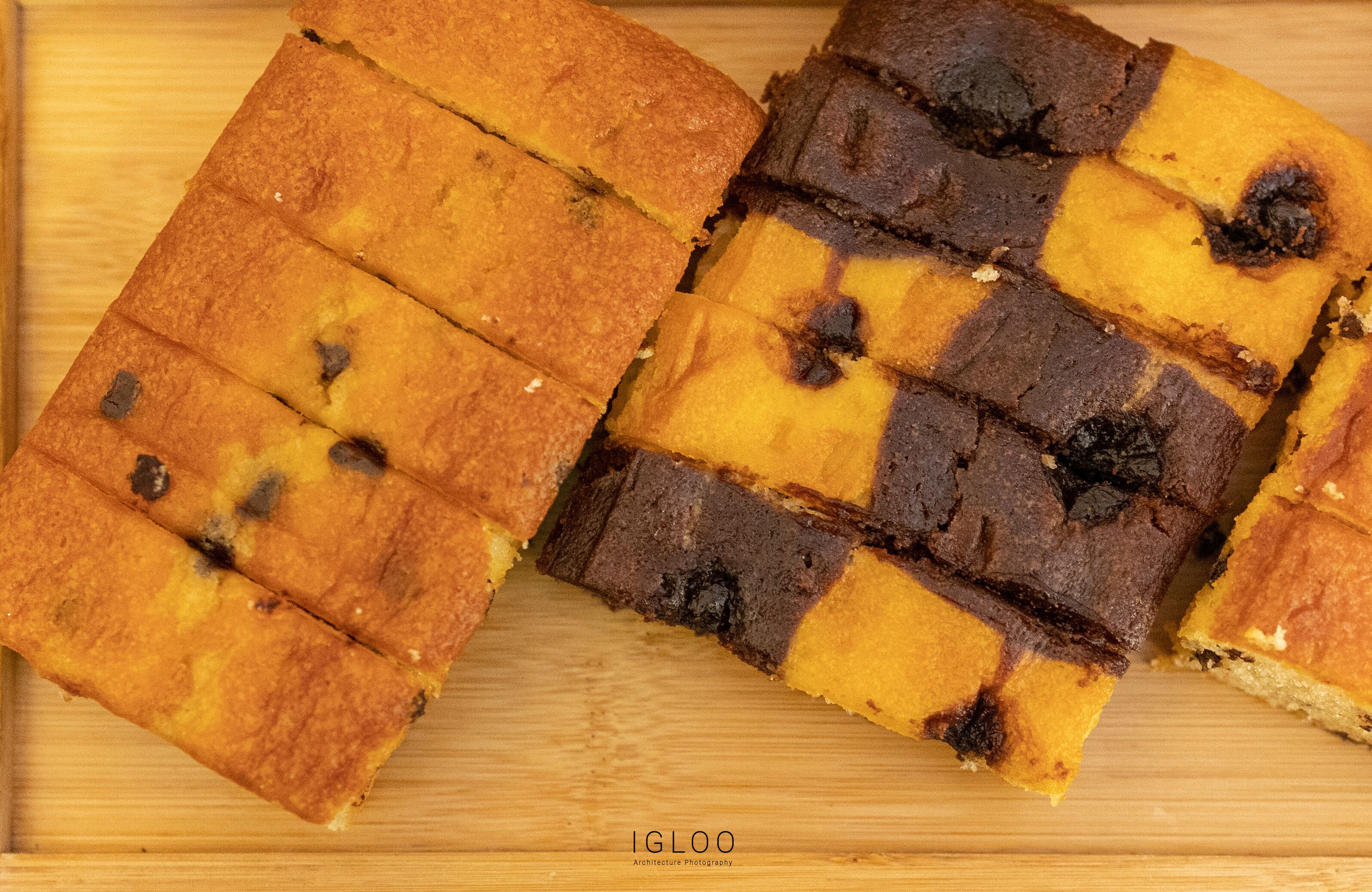 A wooden cutting board with several square pieces of baked good, possibly a dessert, arranged on it.