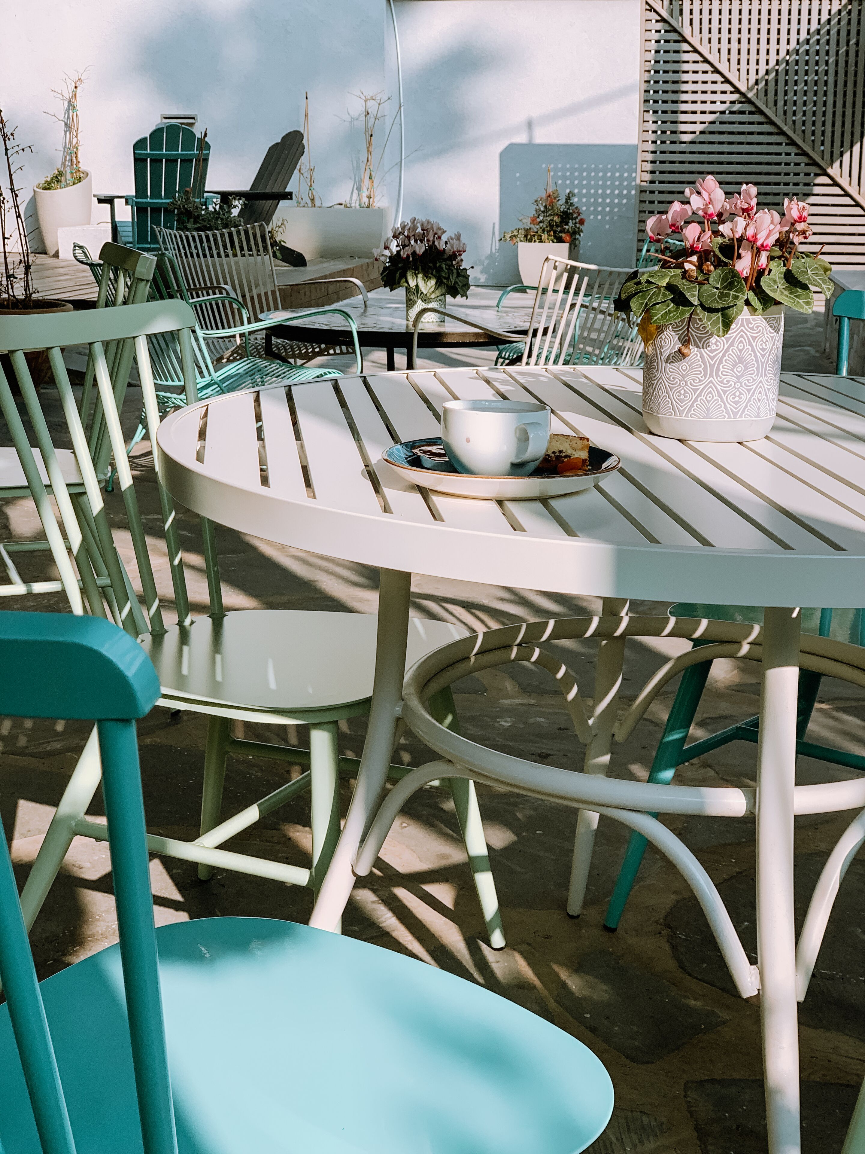 Ein runder Tisch im Freien mit Stühlen, einem Blumentopf und einer Tasse darauf.