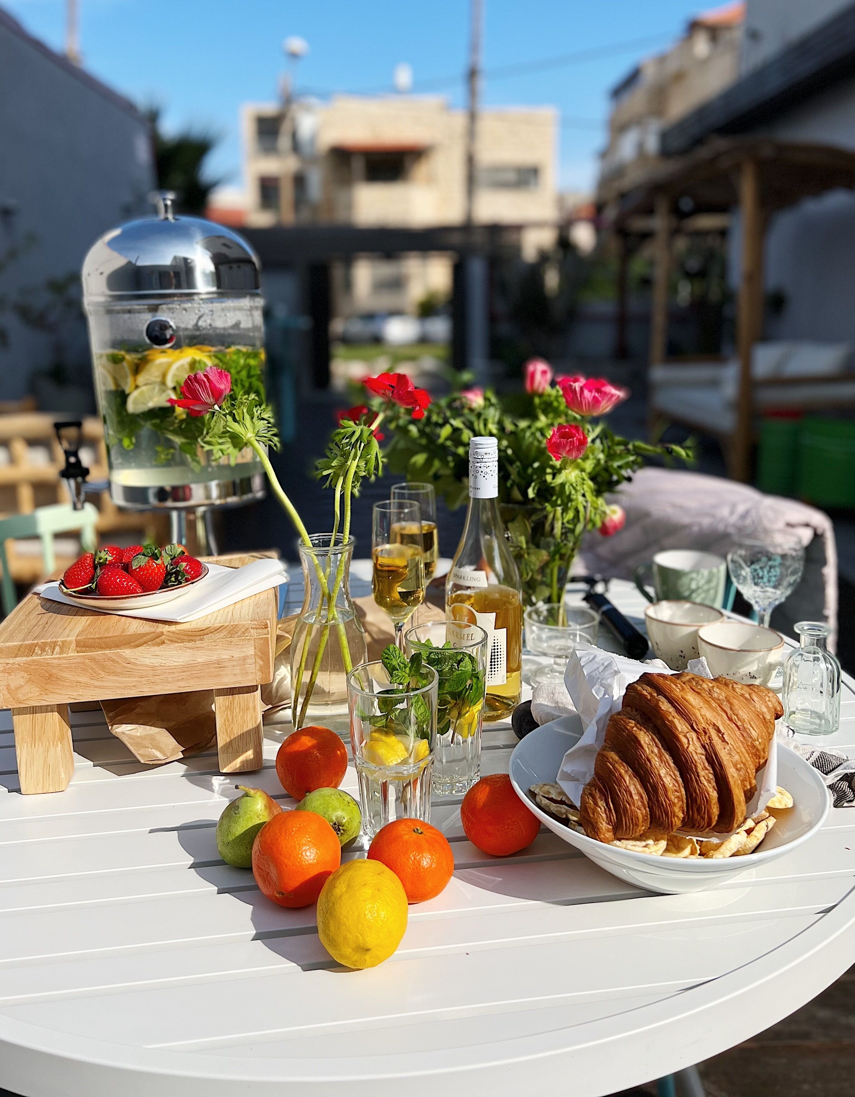 Une table dressée à l’extérieur, avec de la nourriture, des boissons et un distributeur d’eau.