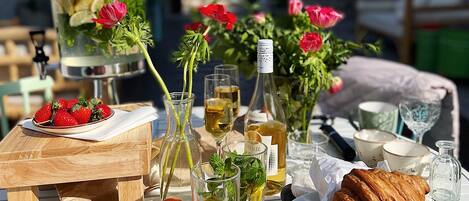 Une table dressée à l’extérieur, avec de la nourriture, des boissons et un distributeur d’eau.