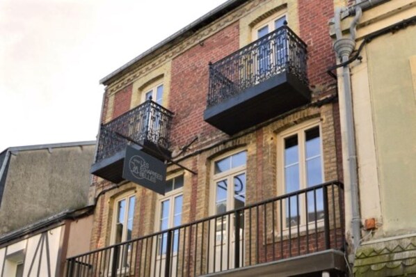 A building with a brick facade, multiple windows, and a balcony with a metal railing.