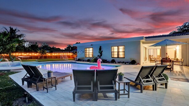Ein Poolbereich mit Liegestühlen, einem Flamingo-Schwimmding und einer Terrasse mit Tisch und Stühlen.