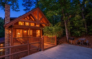 A wooden cabin with a balcony, surrounded by trees. - 3 BR/2.5 BA NEAR PARKWAY, GAME ROOM, FIREPLACE, HOT TUB,REAL LOG CABIN,PETS OK! (Pigeon Forge)