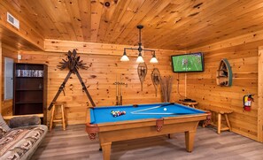 A wooden room with a pool table, a bookshelf, a tripod, and a television. - 3 BR/2.5 BA NEAR PARKWAY, GAME ROOM, FIREPLACE, HOT TUB,REAL LOG CABIN,PETS OK! (Pigeon Forge)