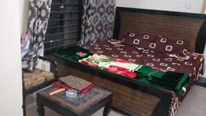 Una habitación con cama, una mesita y una ventana con cortinas.