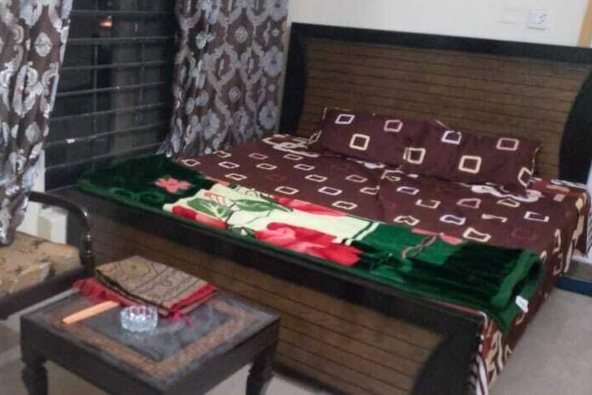 A room with a bed, a small table, and a window with curtains.