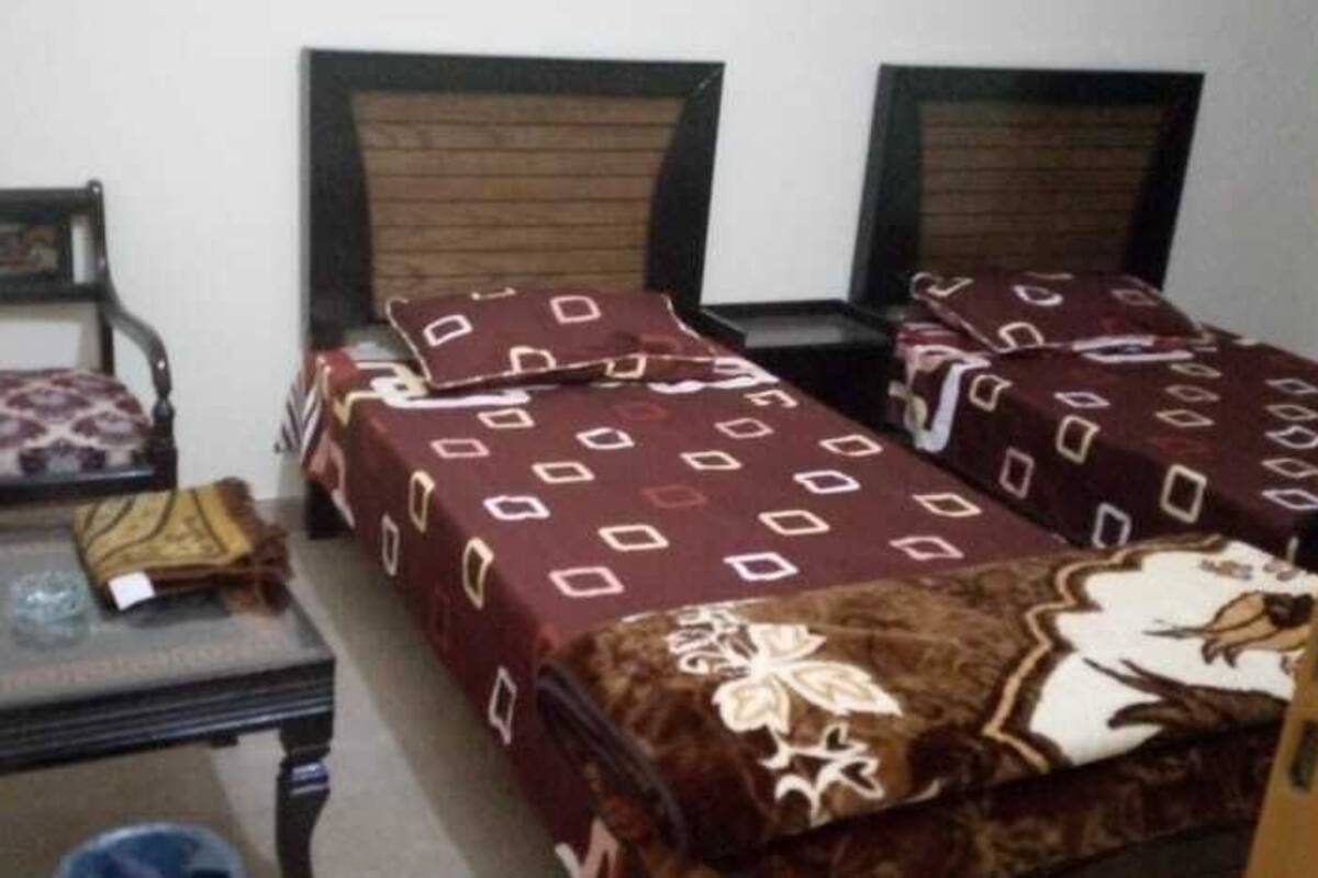 A small room with two beds, a chair, and a table.