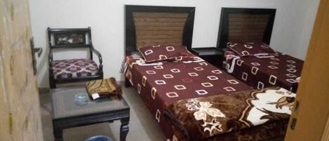 A small room with two beds, a chair, and a table.