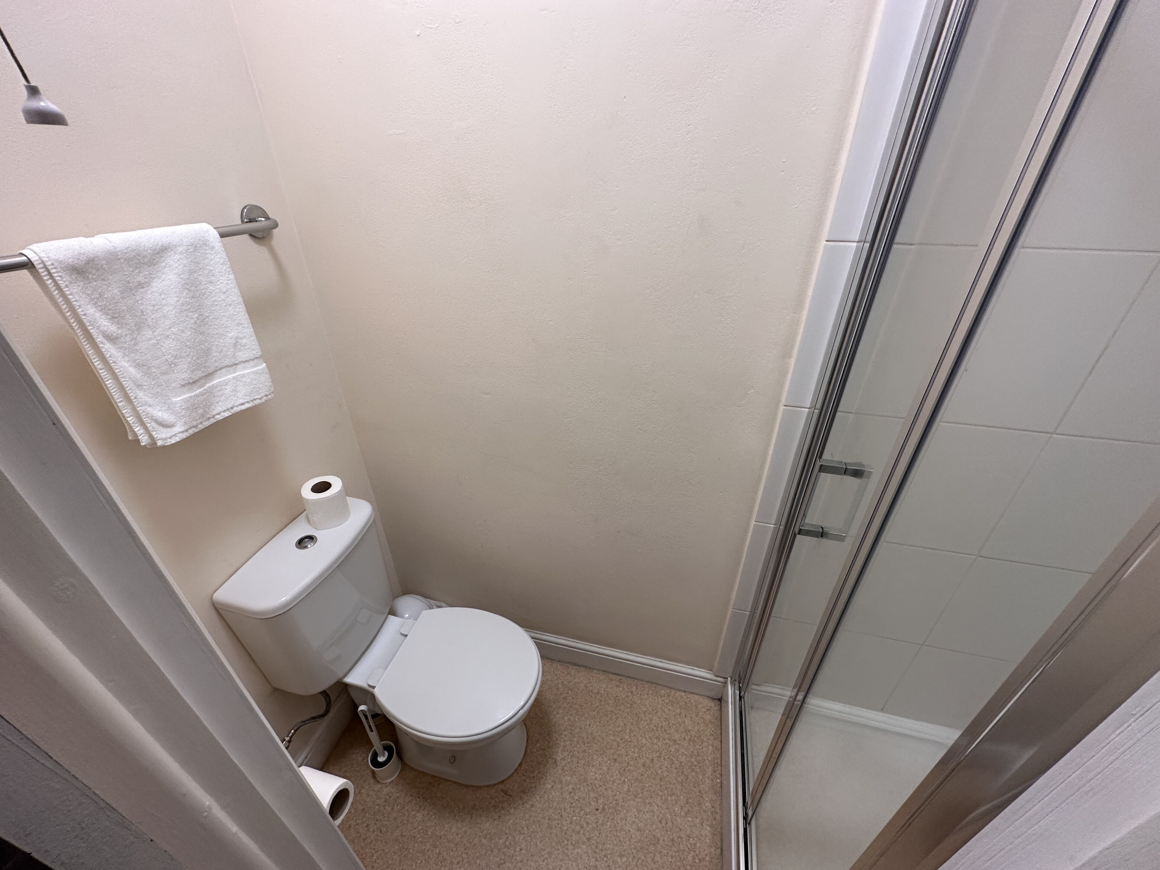 Ein kleines, kompaktes Badezimmer mit Toilette, Dusche und Handtuchhalter.