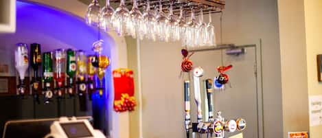 A bar area with a wine glass rack, beer taps, and a cash register.