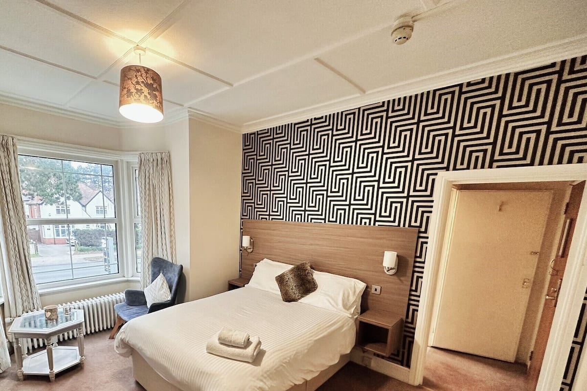 Une chambre d’hôtel avec un lit, une chaise, une table et une vue sur l’extérieur.