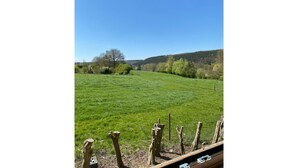 Un campo erboso con una recinzione in legno in primo piano e un cielo azzurro intenso.