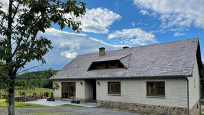Una casa a due piani con fondamenta in pietra e tetto grigio.