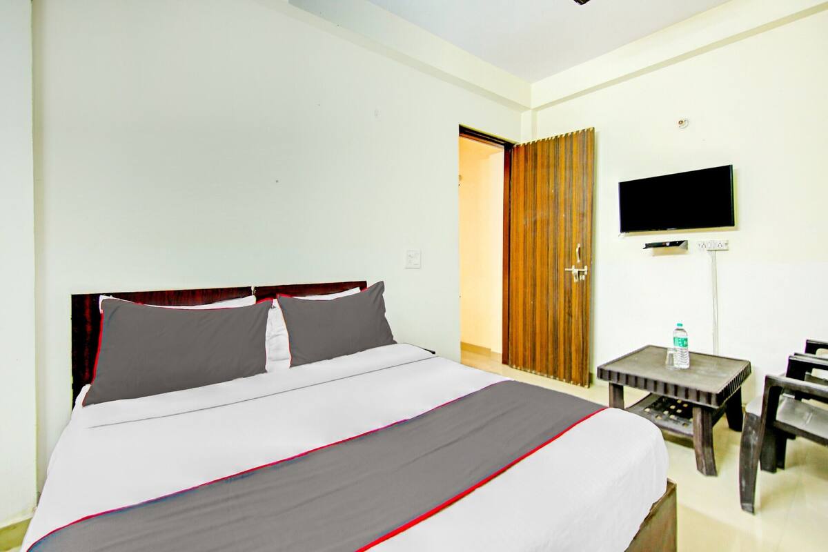 A hotel room with a bed, a TV mounted on the wall, a small table, and a chair.