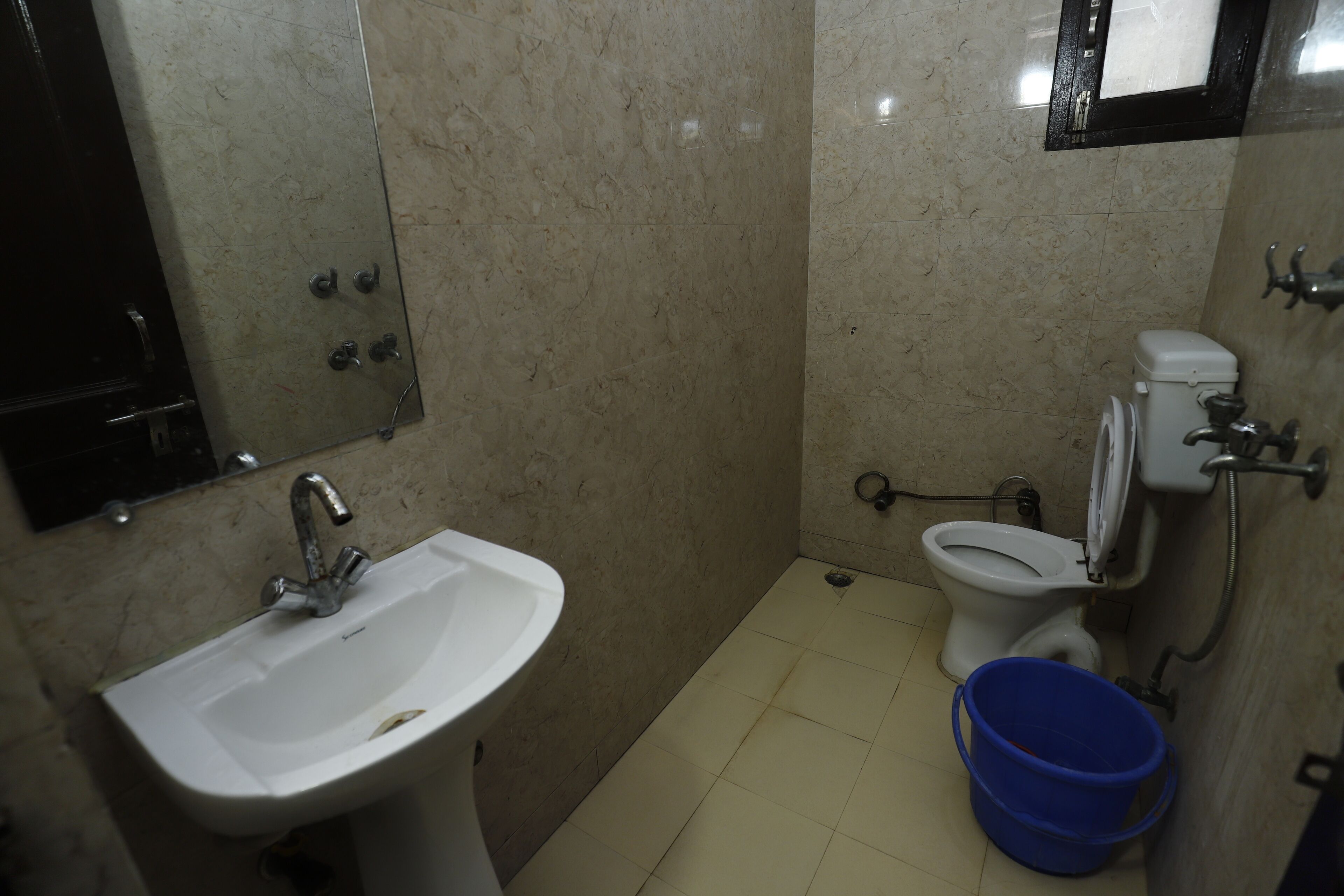 Un baño pequeño con lavamanos, inodoro y un cubo azul.