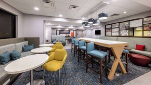 A modern hotel lobby with seating areas, a bar, and a reception desk.