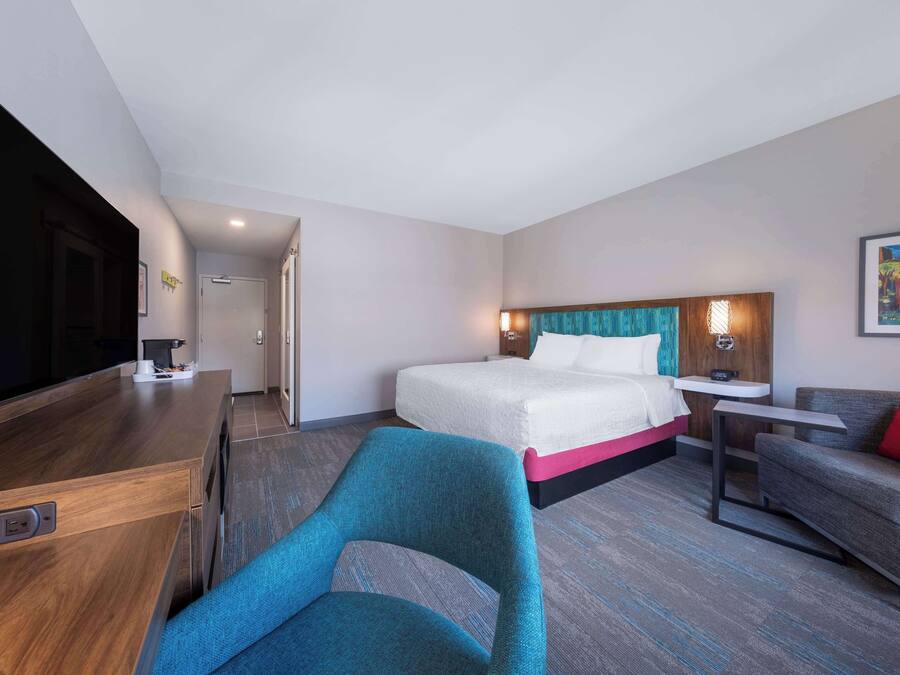 A hotel room with a bed, a desk, a chair, a sofa, and a TV.