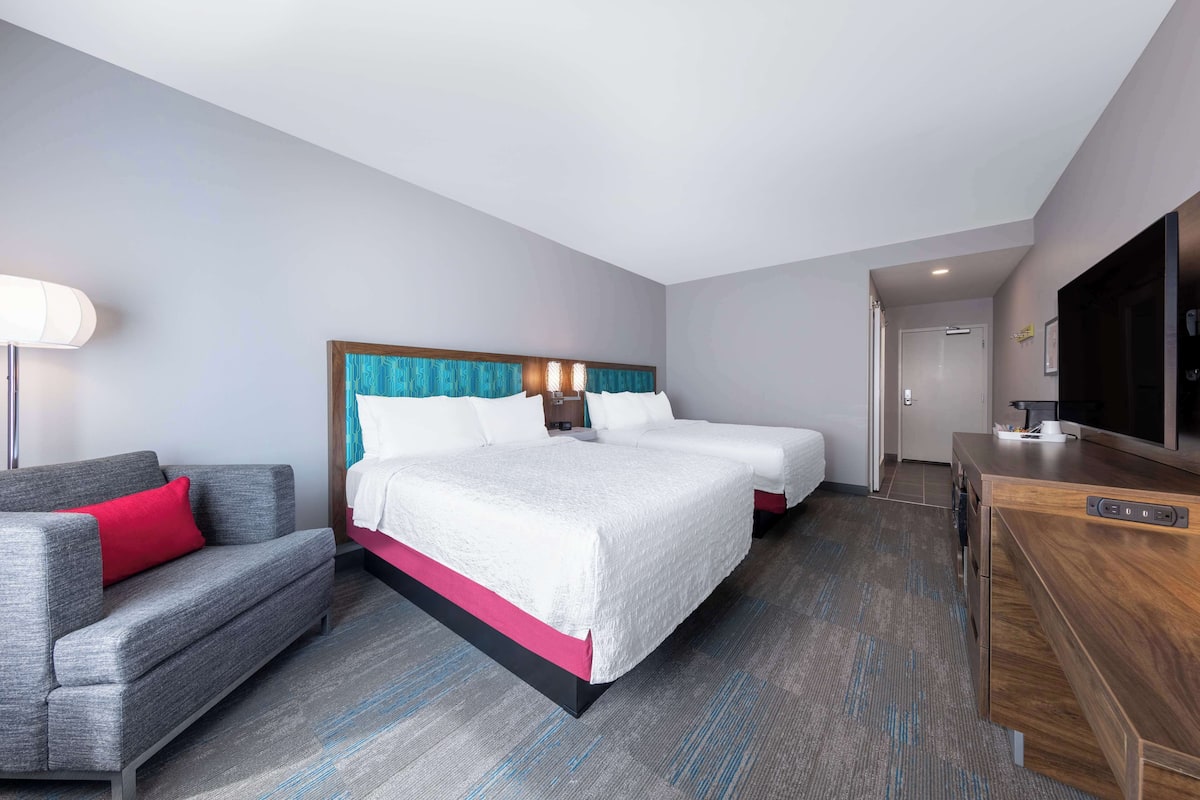 A hotel room with a large bed, a sofa, a desk, and a TV.
