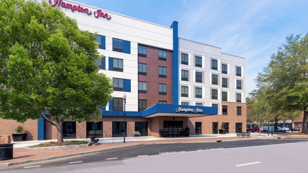 A Hampton Inn hotel with a modern facade, multiple floors, and a prominent signage.