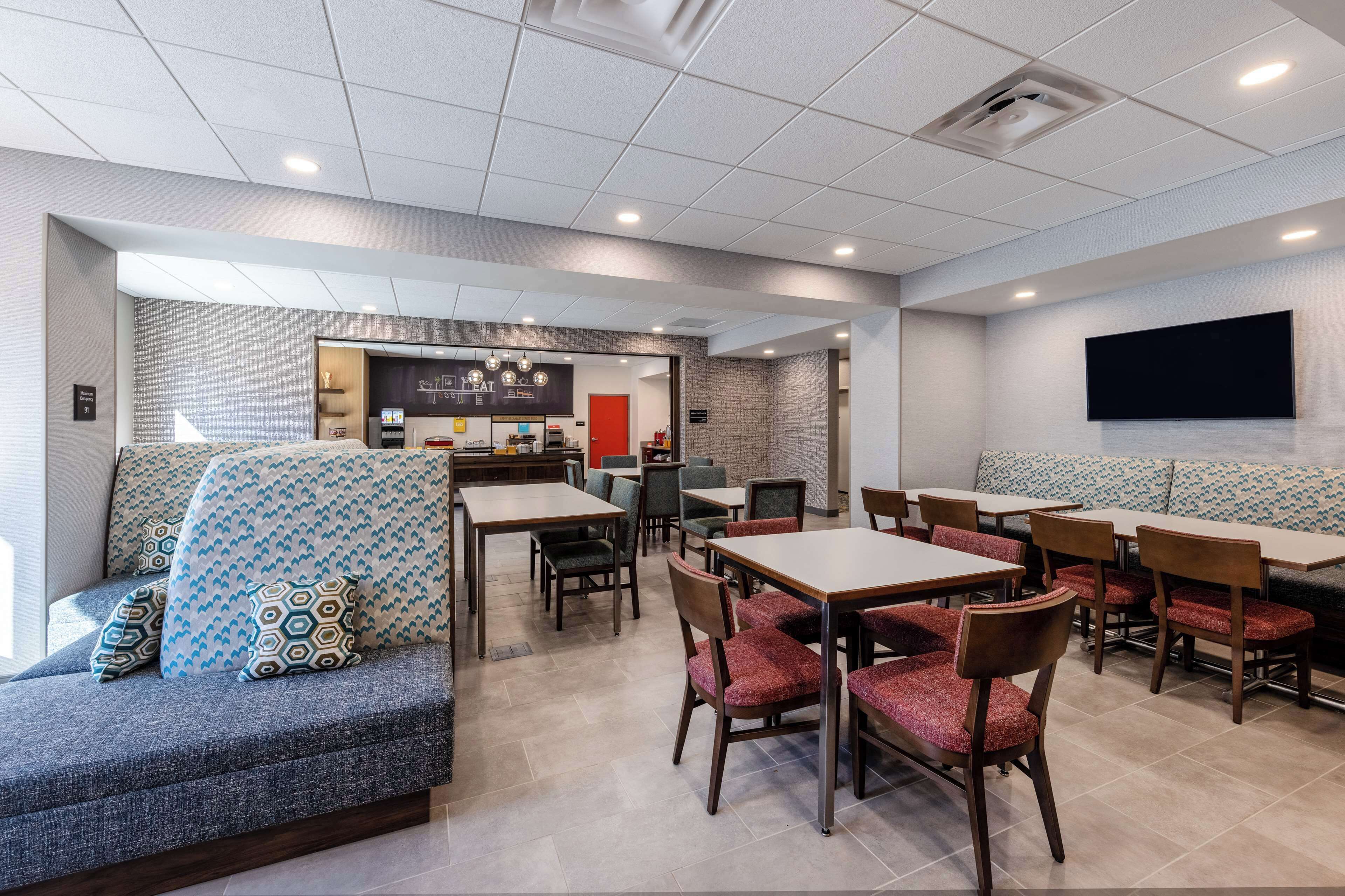 A modern restaurant with a brick wall, a counter, and seating areas with tables and chairs.