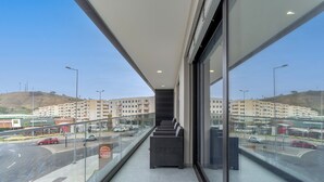 A modern hotel interior with a balcony overlooking a parking area and a view of a hilly landscape. - Apartamento Orquídea (Funchal)
