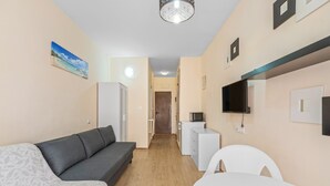 A compact living space with a sofa, a dining table, a kitchenette, and a television. - Holiday Apartment 200 m from the Beach (Torrevieja)