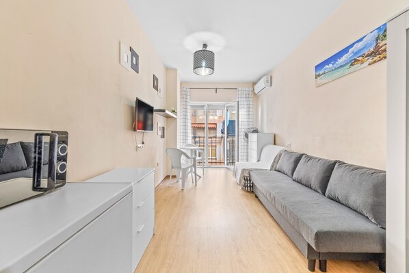 A modern room with a sofa, a TV, a desk, and a chair.