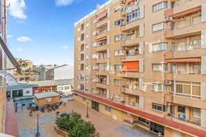 Un immeuble résidentiel à plusieurs étages, doté de balcons, d’une cour intérieure et donnant sur la rue.