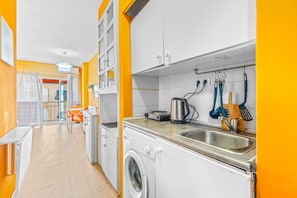 A compact kitchen with a washing machine, a sink, and various utensils.
