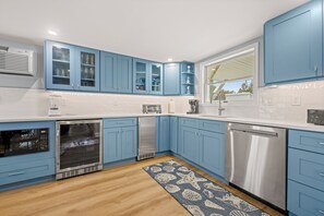 Una cocina moderna con armarios azules, electrodomésticos de acero inoxidable y piso de madera.
