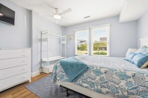 Un dormitorio con cama, armario, ventilador de techo y ventana con persianas.