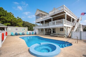 A two-story building with a swimming pool, outdoor seating, and a flag.