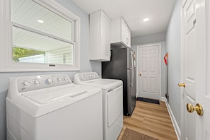 Un cuarto de lavado con lavadora y secadora, un refrigerador y una puerta con manija de latón.
