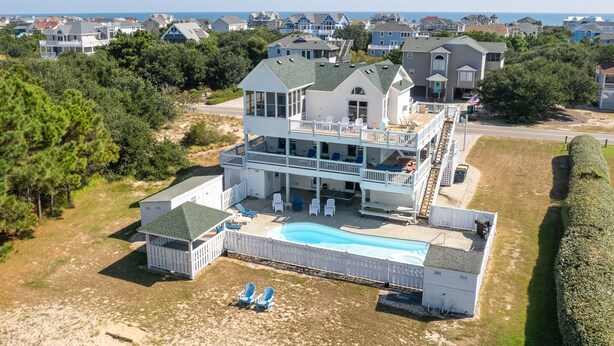 Une grande maison à deux étages dotée d’une piscine, de plusieurs terrasses et offrant une vue sur l’océan.