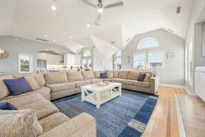 A spacious living area with a sectional sofa, a coffee table, and a large window providing natural light.