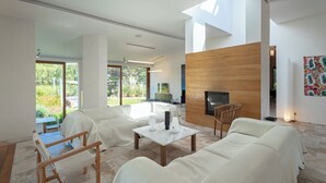 A modern living room with a fireplace, a television, and a dining area with a table and chairs.
