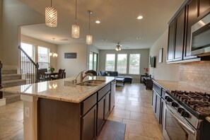 A modern kitchen with a large island, stainless steel appliances, and pendant lighting. - Affordable 3-Bedroom Townhouse With Backyard ~ Double Story (Pet Friendly!) (Rosenberg)