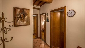 Un pasillo con una puerta de madera, un reloj y un cuadro en la pared.