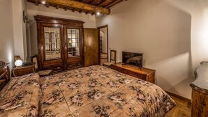 Un dormitorio con una cama grande, un armario de madera y una televisión.