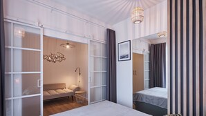 A modern bedroom with a large bed, a sofa, a wardrobe, and a mirror.