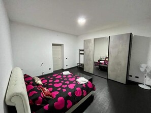 A modern bedroom with a bed, a mirror, and a fan.