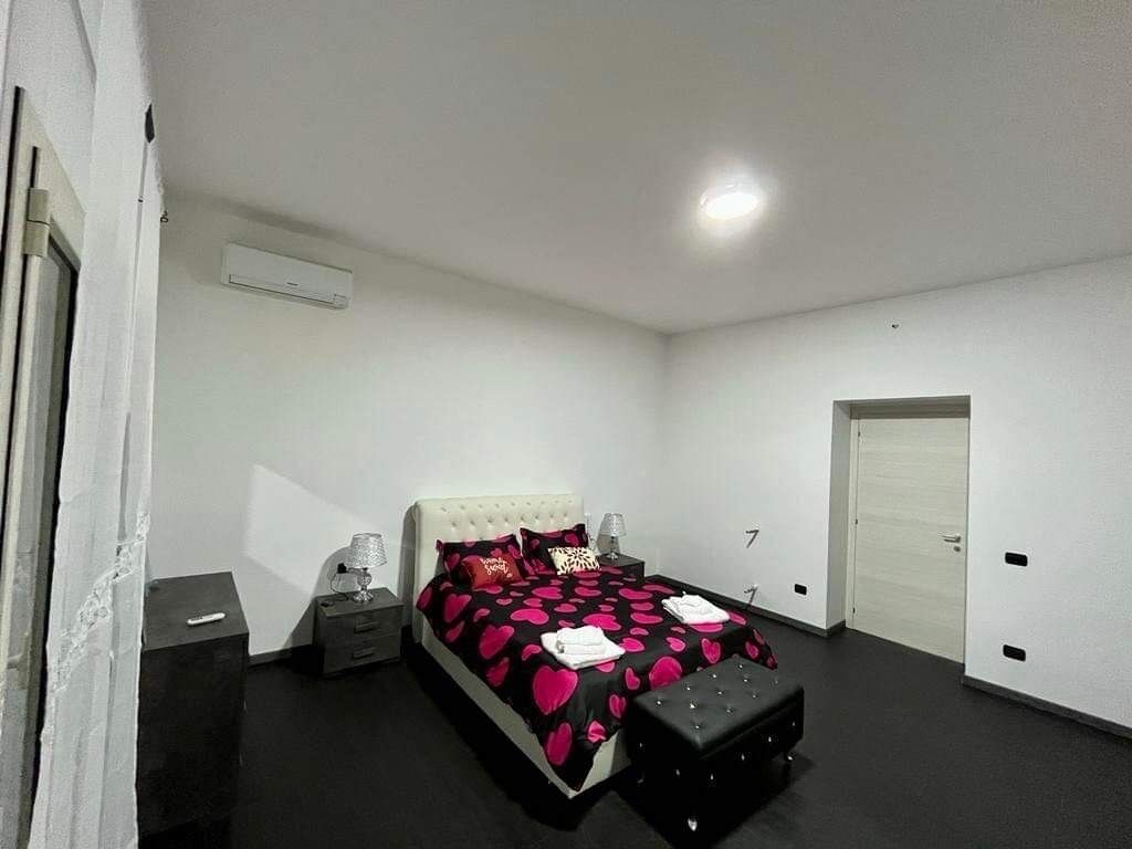 Un dormitorio con cama, mesitas de noche, armario y equipo de aire acondicionado.